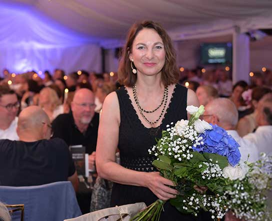 Caroline Kratzsch von Körpernah nach der Eröffnungsrede mit einem Blumenstrauß in der Hand.